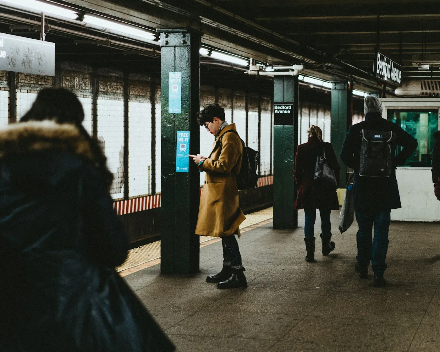 A commuter using a smartphone inside a busy train station