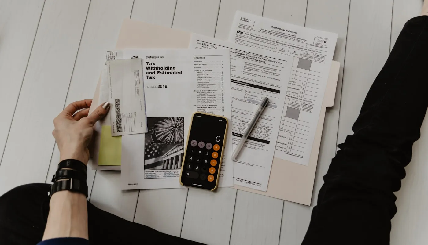 A person reviewing finance documents with a calculator and pen