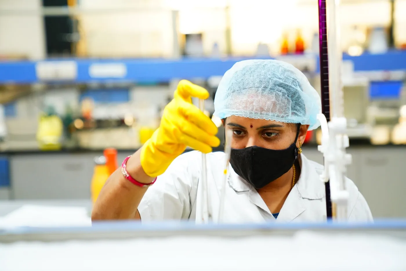 A researcher in a white coat working at a laboratory bench in India