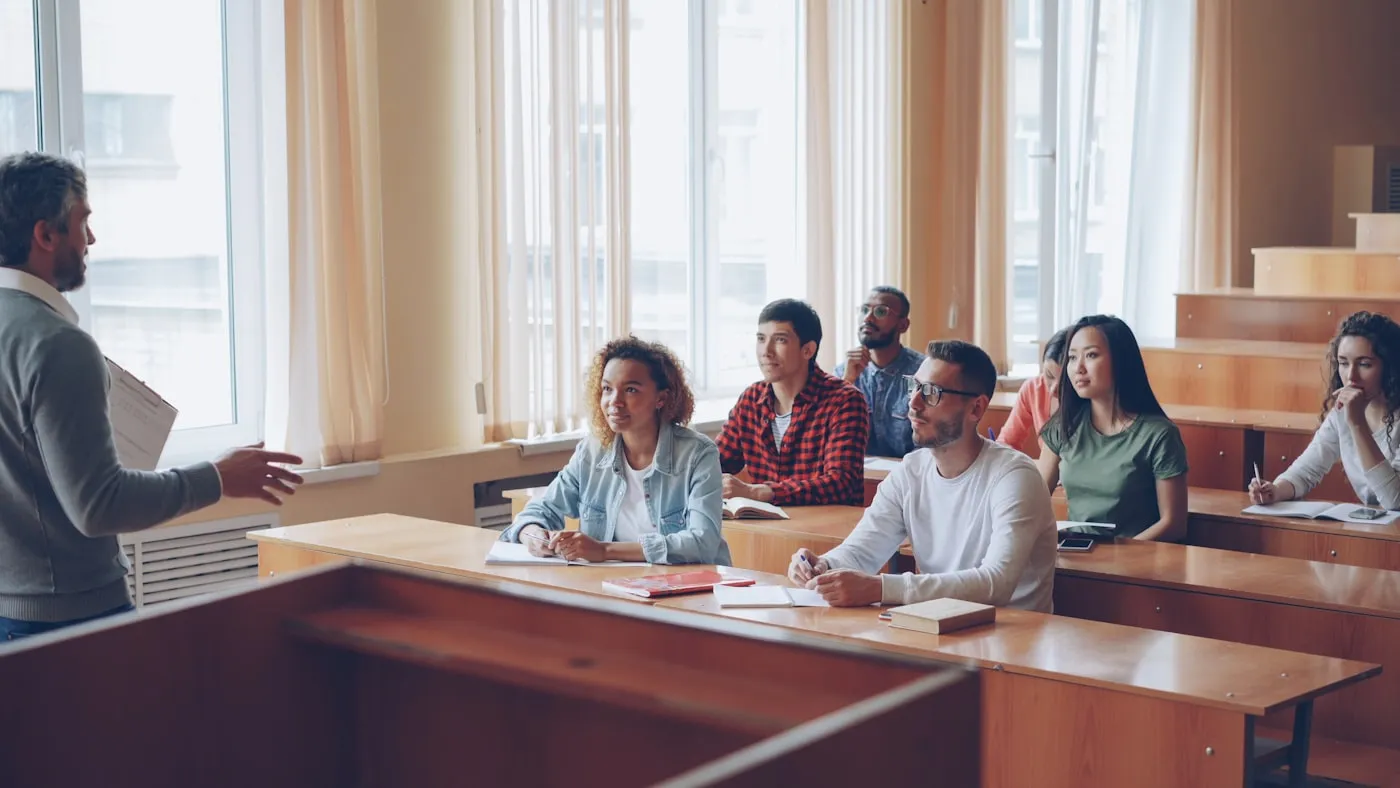 A professor lecturing to students in a large classroom
